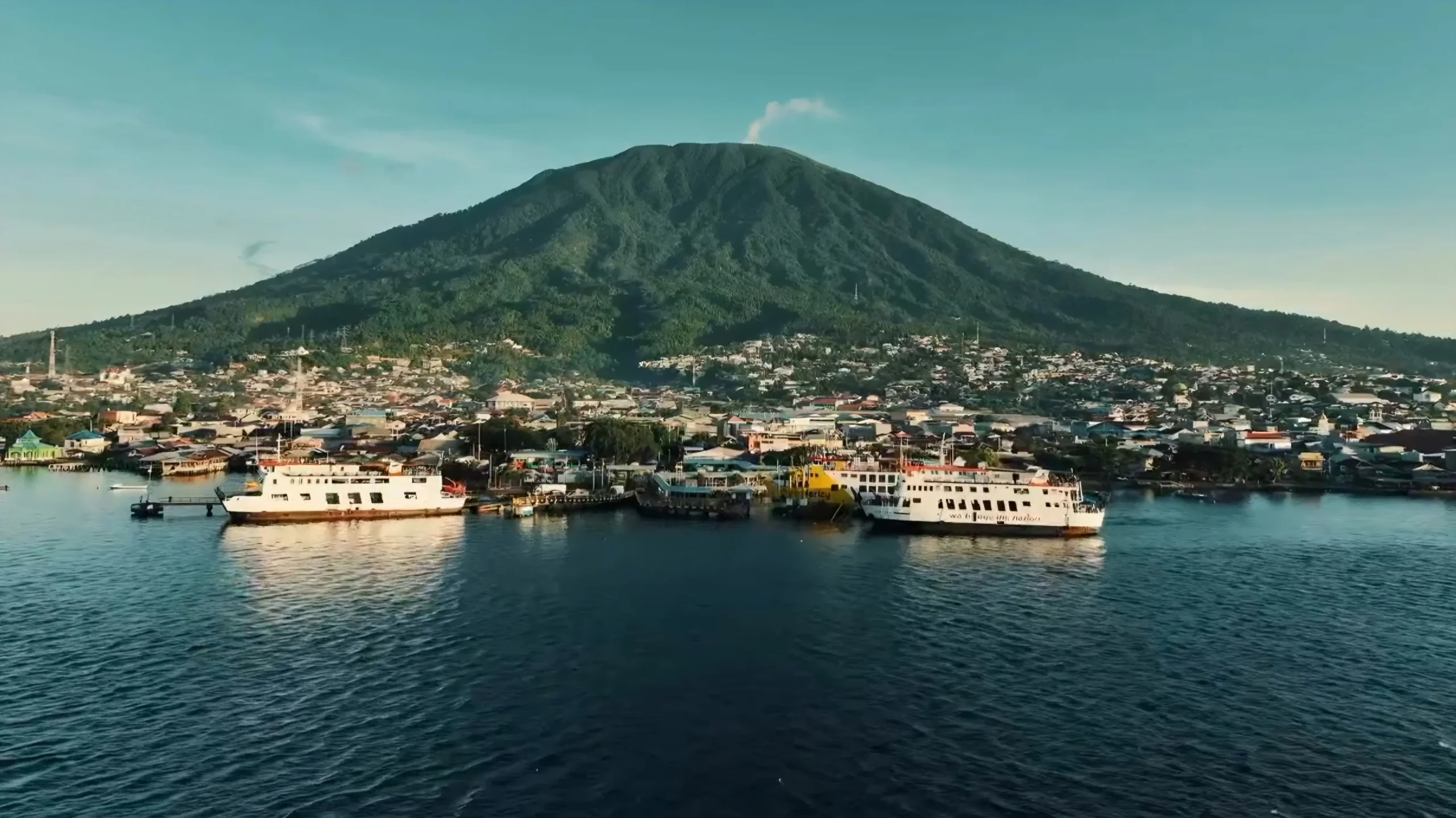 Pemandangan pelabuhan Ternate latar Gunung Gamalama pusat perdagangan rempah Maluku Utara.