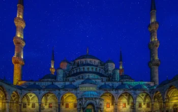 Ilustrasi masjid dengan kubah bercahaya di bawah langit malam bertabur bintang untuk menyambut awal Ramadhan 1447 Hijriah.